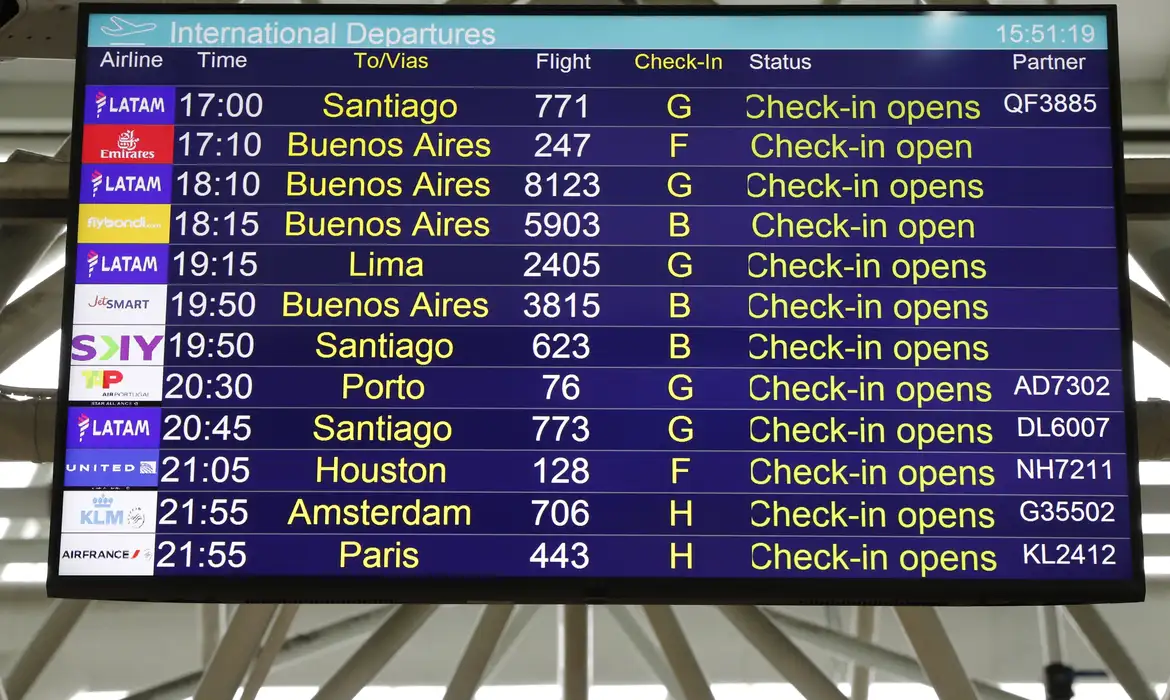 Imagem de um telão de aeroporto, indicando horários de voos.